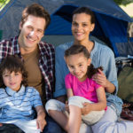 Happy family on a camping trip in their tent on a sunny day